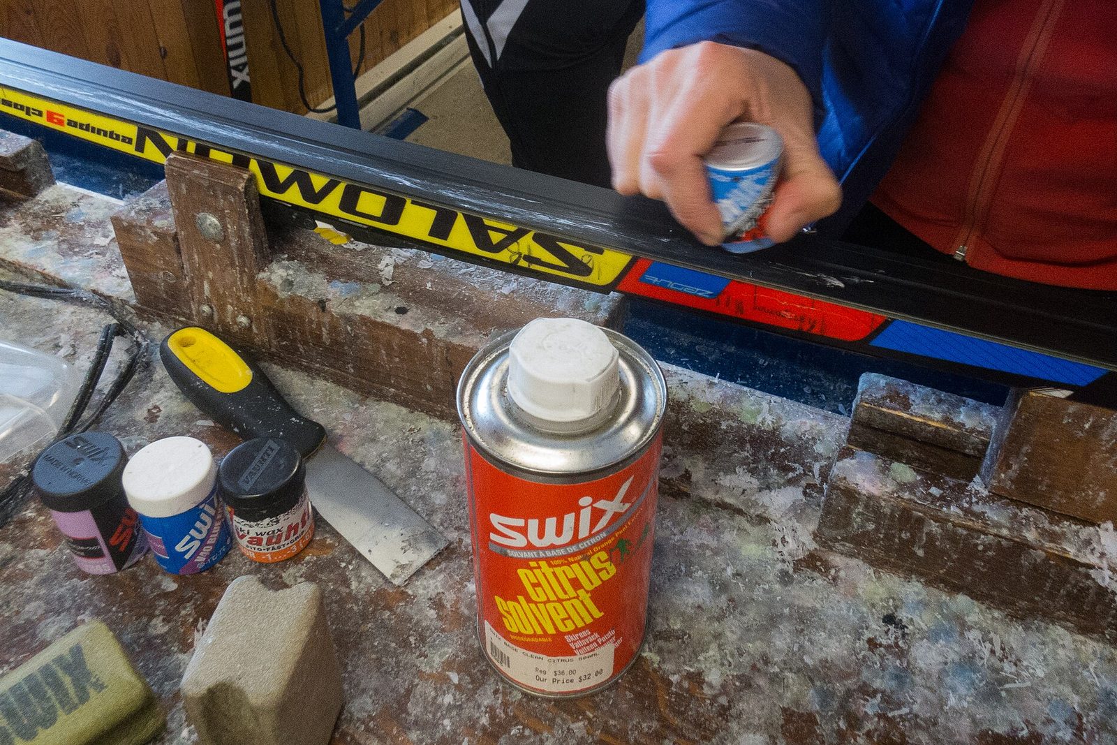 Hot wax being applied to a ski base on the workshop bench
