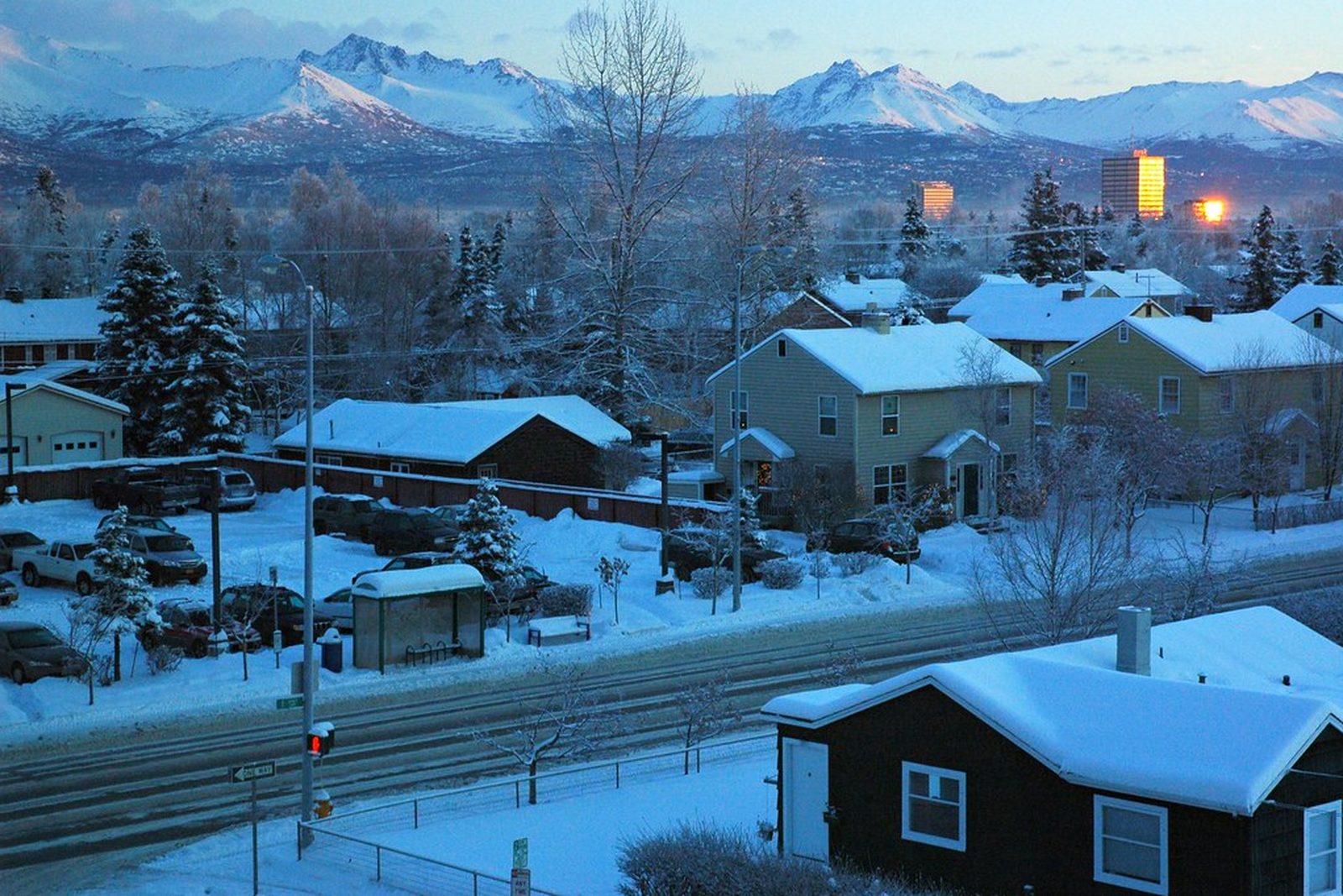 Alpine village at dusk under snow, mountains behind